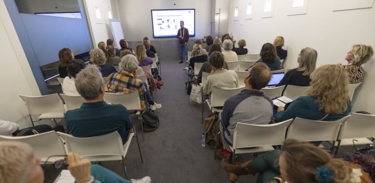 Bezoekers zitten in de zaal en luisteren naar het verhaal van Cor Lievaart