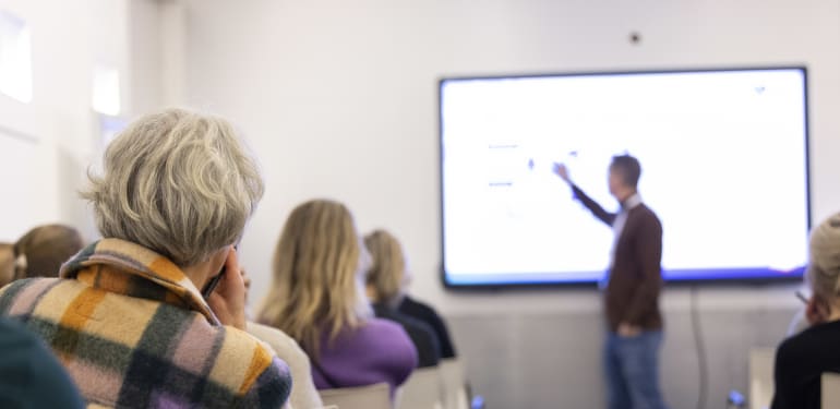 Bezoekers van de werksessie luisteren naar presentatie