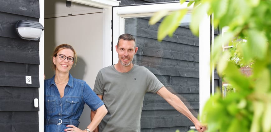 Projectleider Willemijn en casemanager Mike van Prinsenstichting staan bij de voordeur van een tiny house