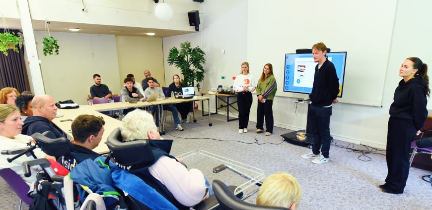 Vier zorgprofessionals presenteren voor een groep met ervaringsdeskundigen.